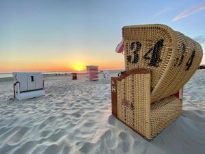 ボルクムにあるBORKUMUNTERKUNFT - WOH7 - IM HERZEN DER INSELの夕日のビーチに座る籐の椅子