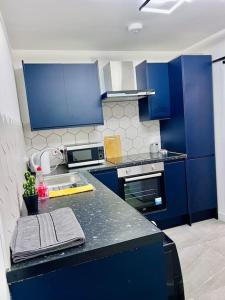 een keuken met blauwe kasten en een zwart aanrecht bij City Studio Apartment Swansea - Includes Free Parking in Swansea
