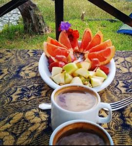 トラピチェにあるFrente al lagoのコーヒーと一緒にテーブルの上にフルーツの盛り合わせ