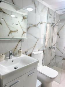 een badkamer met een wastafel, een toilet en een spiegel bij Joyful Apartment Tirana in Tirana