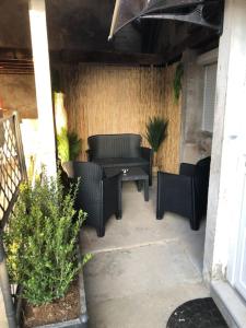 eine Terrasse mit Korbstühlen und einem Tisch auf der Veranda in der Unterkunft La Petite Maison du Canal in Digoin