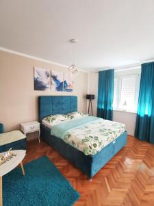 a bedroom with a blue bed and blue curtains at City Center Apartment JOTIC in Pirot