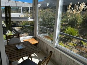 a balcony with a table and chairs and two windows at Departamento El Chiriwe in Puerto Varas