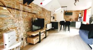 - un salon avec une télévision et un mur en briques dans l'établissement Appartement de Charme - Centre Ville, à Châteaubriant