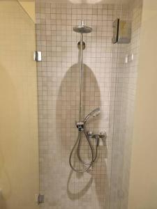 Elegant Suites Murten في مورتين: دش في الحمام مع جدار من البلاط