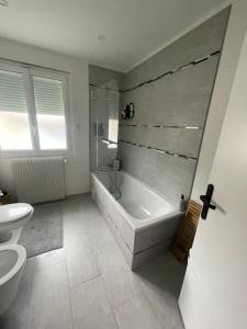 a bathroom with a tub and a toilet and a sink at DD HOME près PARIS in Viarmes