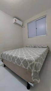 uma cama num quarto branco com uma janela em Apto Familiar em Aracaju