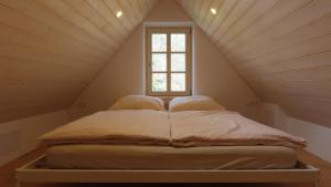 a bed in a attic with a window at Domek Kavalírek in Lipova Lazne