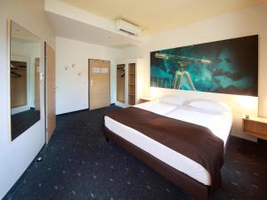 ein Schlafzimmer mit einem großen Bett mit einem großen Gemälde an der Wand in der Unterkunft B&B Hotel Jena in Jena