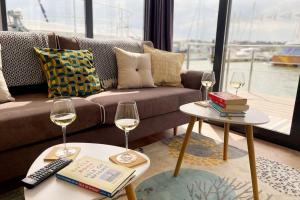 a living room with a couch and two glasses of wine at Yarmouth Waterlodge Floating Apartments 2 in Yarmouth
