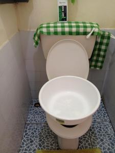 a bathroom with a toilet with a green and white towel at Cosmic Haven Studio in Mombasa