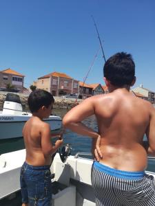 two young boys standing on a boat in the water at The Ferry House in São Jacinto