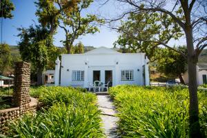 a white house with a pathway leading to it at Landskroon Cottage in Paarl