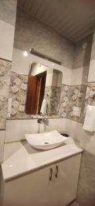 een badkamer met een wastafel en een spiegel bij Pomme Homestay in Kasauli