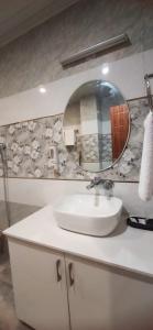 een badkamer met een witte wastafel en een spiegel bij Pomme Homestay in Kasauli