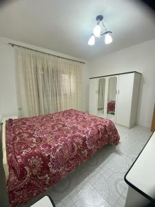 een slaapkamer met een bed met een rode deken erop bij Tota apartments in Shkodër