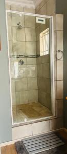 a shower with a glass door in a bathroom at Bird Song in Roodepoort
