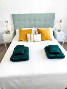 uma grande cama branca com duas almofadas verdes em Hope house Lanzarote em Puerto del Carmen