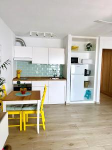 uma cozinha com armários brancos, uma mesa e cadeiras amarelas em Hope house Lanzarote em Puerto del Carmen