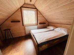 Ce lit se trouve dans une chambre en bois dotée d'une fenêtre. dans l'établissement Domki Strefa Ciszy Bieszczady, à Terka