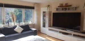 a living room with a large flat screen tv at Moderne Zimmer im Grünen, mit Park- und Meer-Nähe in Bad Zwischenahn