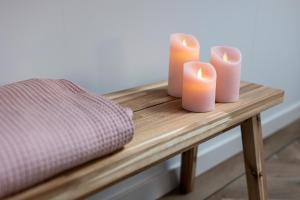 three candles sitting on a wooden table with a pillow at Jantje Slot Hoeve in Oosterzee