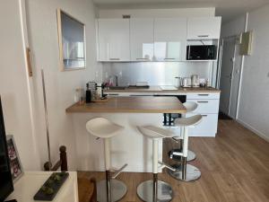 a kitchen with white cabinets and bar stools at Prestige Ocean Apartment - 50 m2 - 2 chambres in Lacanau +8 photos