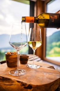 a person pouring wine into two glasses on a table at Unterkircher Chalet in Arriach