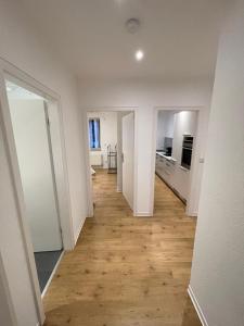 an empty hallway of a white apartment with wooden floors at Klein aber fein — citynah in Unna