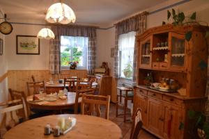 um restaurante com mesas e cadeiras de madeira e janelas em Gästehaus Taucher em Bad Blumau