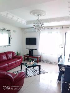a living room with a red couch and a table at Appartement luxueux de Bonaberi in Douala