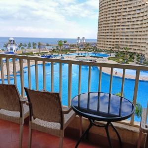 a balcony with a table and chairs and a pool at porto sokhna Pyramids Apartment Familis in Ain Sokhna