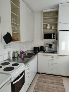 - une cuisine blanche avec cuisinière et évier dans l'établissement Yksiö Iisalmen keskustassa., à Iisalmi