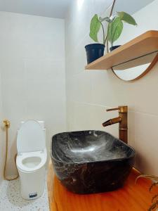 a bathroom with a black bath tub next to a toilet at The Hue Homestay in Thôn Dương Xuân Hạ