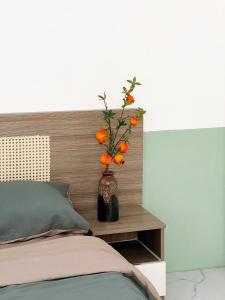 Thôn Dương Xuân Hạ的住宿－The Hue Homestay，睡床旁的床头柜上带橙花的花瓶