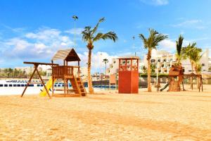 einen Spielplatz am Strand mit Palmen und einem Gebäude in der Unterkunft فاوتشر فان بيتش in Durrat Al-Arus