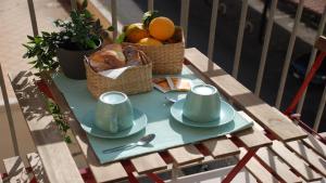 a table with a plate of bread and cups and a basket of fruit at Roma Apartment in Sperlonga