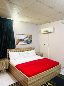 a bedroom with a large bed with a red blanket at OD-V!CK'S BUDGET ROOMS, 24HR POWER, SECURITY, DSTV in Abuja