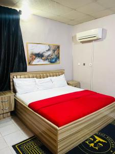 a bedroom with a large bed with a red blanket at OD-V!CK'S BUDGET ROOMS, 24HR POWER, SECURITY, DSTV in Abuja