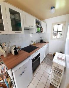 une cuisine avec des armoires blanches et un comptoir en bois dans l'établissement Charment Cottage de 45 m2 Rénové et moderne, à Villers-sur-Mer 50 autres photos