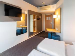 a hotel room with a bed and a desk at B&B HOTEL Frankfurt-Hahn Airport in Lautzenhausen