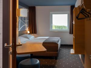 a hotel room with a bed and a window at B&B HOTEL Frankfurt-Hahn Airport in Lautzenhausen