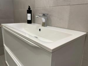 a white bathroom sink with a bottle of wine on it at Beautiful Baslow Bolthole (close to Chatsworth) in Baslow
