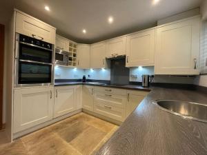 a kitchen with white cabinets and a stainless steel sink at Beautiful Baslow Bolthole (close to Chatsworth) in Baslow
