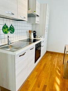 una cucina con mobili bianchi e pavimento in legno di Casa Fibonacci a Pisa