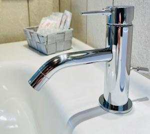 un lavandino in bagno con rubinetto cromato e cesto di Casa Fibonacci a Pisa