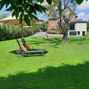 two lounge chairs and an umbrella on a lawn at B&B Gellick in Lanaken