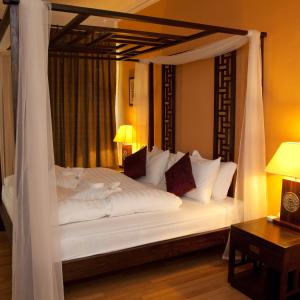 1 dormitorio con cama blanca con dosel y almohadas blancas en Villa Molek, en Pantai Cenang