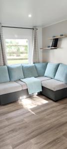 a blue couch in a living room with a window at Mobil-home 6 personnes - Camping SIBLU Bonne Anse Plage in Les Mathes