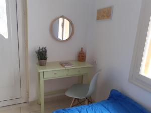 a bedroom with a table and a chair and a mirror at Kampos Rooms in Palaiochóra